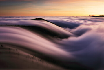 Mountain landscape above clouds at sunset in Slovakia with forest and sun