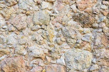 The uneven surface of the wall with ancient masonry of stones and cobblestones