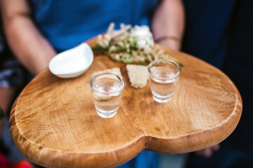Wedding tradition in Poland and Russia. Parents welcome bride and groom with bread, vodka and salt. Decorative tray with food and alcohol. European culture background. Heart shape wooden tray. - obrazy, fototapety, plakaty