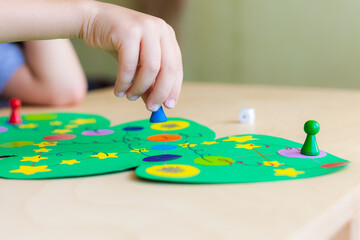 child hand rolls the dice and moves the chip across the Christmas playing field