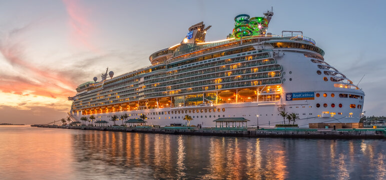Nassau, Bahamas - June 22, 2019: Beautiful panoramic shot of Mariner of the Seas cruise ship docked at Prince George Wharf at sunset. Reflections in the water in the foreground