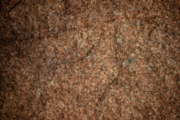 Red granite texture. A variegated, spotted background of red (brown) granite. The stone granite surface of brown-gray color. Surface view of granular igneous rock