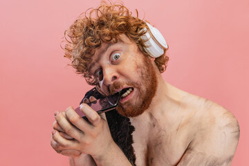 Cropped portrait of man in character of primitive human, neanderthal in headphones biting phone...