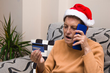 senior woman at christmas with mobile phone and credit card buying online
