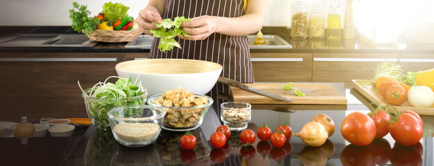 Closeup hand mix the vegetables in a salad bowl. Morning atmosphere in a modern kitchen.