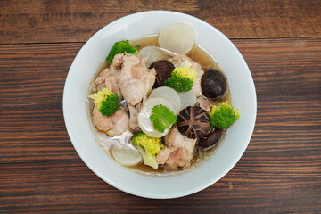 chicken and vegetable soup in white cup food on wooden table
