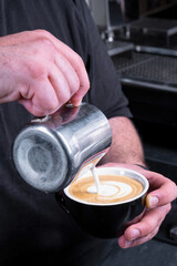 Making of latte art by barista focus in milk and coffee.