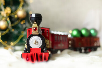 A photo of a Christmas train with a selective focus, a children's toy and a Christmas decoration.