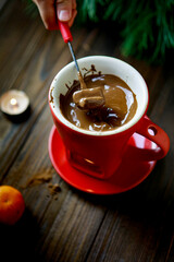 Cozy fondue mug with chocolate and burning candle, winter atmosphere