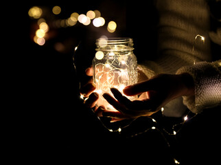 Hands holding a jar with a garland