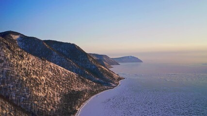 Aerial bird eye view. Snowy mountain range beside frozen ice lake at golden hour - Powered by Adobe