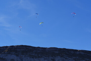 Fototapeta na wymiar Paraglider flying over mountains in summer day in front of the mountain