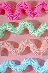 Curved pink blue mint antistress pop tube toy with shadow on pink background. Bright kid toy. Wallpaper 