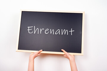 Zwei Hände halten eine Tafel hoch auf der Ehrenamt steht