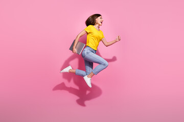 Photo of shiny sweet woman wear yellow outfit jumping high running fast holding modern device empty...