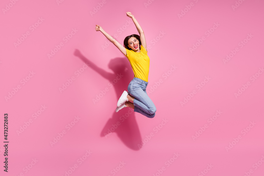 Canvas Prints Photo of sweet lucky young woman wear yellow outfit jumping high rising arms smiling isolated pink color background