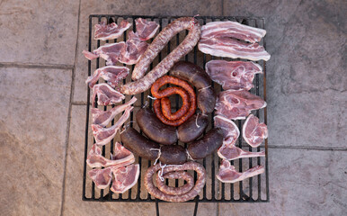 Fototapeta na wymiar Grill full with different types of raw meat ready for getting cooked in the barbecue. Close up.