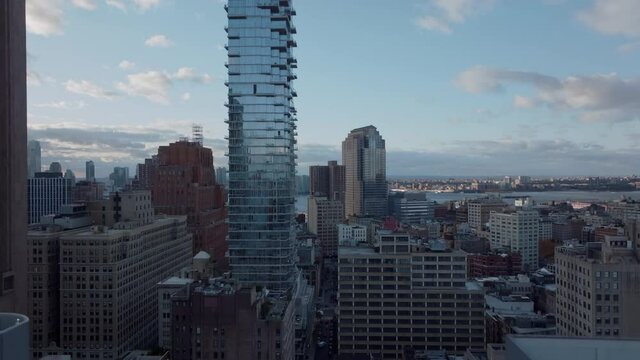 Landing footage in city. Modern glass facade of tall Jenga building reflecting sky. Manhattan, New York City, USA