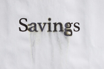 Word "Savings" is written on a paper background with with traces of water. Concept of economy falling and savings