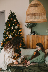 Happy young woman with cute teenage daughter in christmas interior on bed