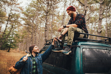 Two millennial man hiking in a forest, drinking beer and having fun.