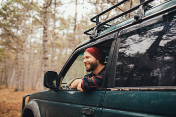 Millennial man travelling off-road by car in a forest. Wanderlust concept.
