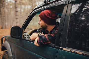Millennial man travelling off-road by car in a forest. Wanderlust concept. © polinaloves