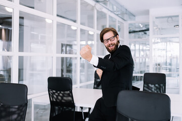 Enthusiastic excited male winner dancing in the office laughing celebrating work achievement,...