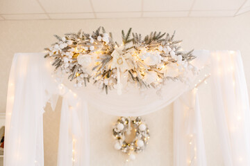 Romantic bed with canopy decorated for New Year Celebrating. Bedroom in light colors with a lot of garland lights . Christmas mood at home. White bedroom and Christmas spruces. Romantic interior.