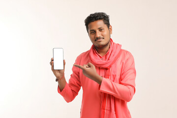 Young indian farmer showing smartphone and giving expression on white background.