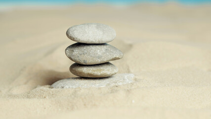 Fototapeta na wymiar Pyramid of stones on the sea sand.