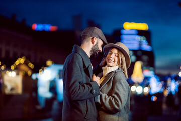 Affectionate couple flirting outdoors on Valentine's day. A young happy couple standing on the street at night and flirting on Valentine's day.