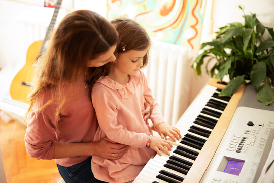 Woman And Girl Playing A Piano. Beautiful Mom Teaching Her Daughter Playing A Piano.	