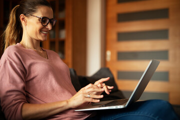 Woman working on laptop from home. Beautiful woman relaxing at home.