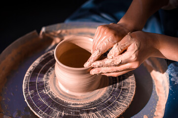 Women hands. Potter at work. Creating dishes. Potter's wheel. Dirty hands in the clay and the potter's wheel with the product. Creation. Working potter.