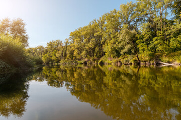 Moody and calm slow river with reflection of trees