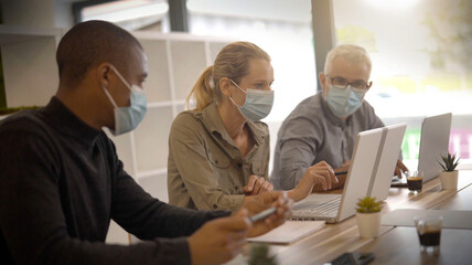 Fototapeta na wymiar team working in an office wearing covid-19 pandemic masks