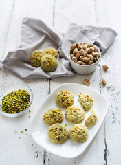 pistachios cookies on the plate and ingredients on the white wooden background