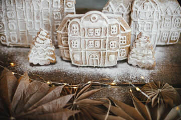 Christmas gingerbread houses and tree on rustic wooden table with stars and lights. Atmospheric moody image. Winter holiday preparation and traditions. Merry Christmas! Xmas cookies village scene