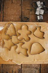 Gingerbread dough with christmas metal cutters on wooden board flat lay. Atmospheric Moody image....