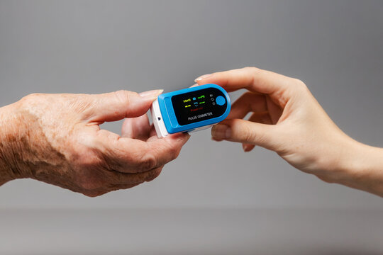 The hands of a young and an elderly woman hold an oximeter. Close-up. Healthcare concept