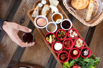 Delicious traditional turkish breakfast with hand holding turkish tea on the wooden table.