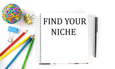 Notebook ,pencils,pen and rubber band with text FIND YOUR NICHE on the white background