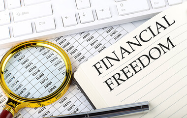 FINANCIAL FREEDOM text on the notebook with chart, magnifier,keyboard and pen