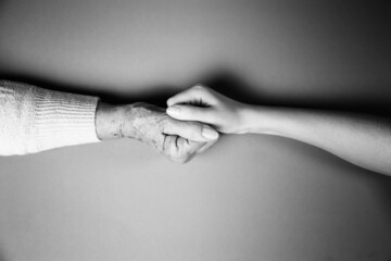Young and senior women holding hands each other. Monochrome. Flat lay. The concept of International Day of Older Persons