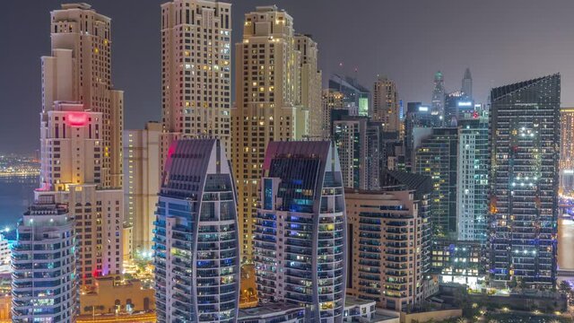 Dubai Marina skyscrapers and JBR district with luxury buildings and resorts aerial timelapse during all night with lights turning off