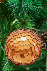 Gold polished metal bauble decorated on Christmas tree. Spherical decoration are used to festoon artificial Xmas tree.