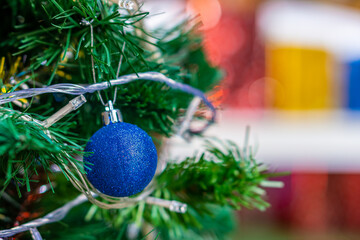 Blue glitter bauble decorated on Christmas tree. Spherical decoration are used to festoon artificial Xmas tree.
