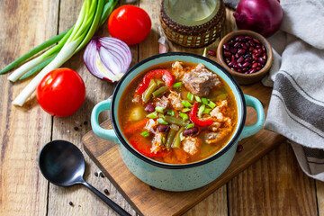Traditional English thick soup with beef, beans and vegetables on a wooden table. Hot dinner or lunch.