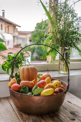 Fruits and vegetables in a big copper bowl with country view from the window